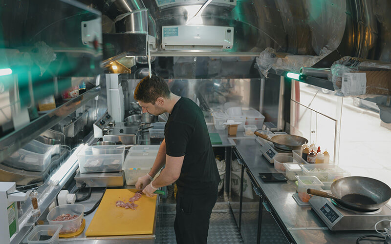 Ghost kitchen cluster with dense stainless steel cooking stations and heavy-duty ESP ventilation